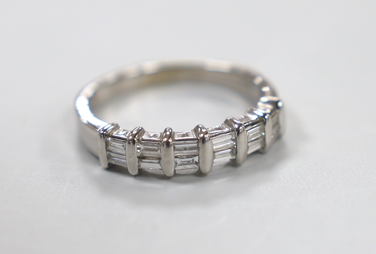 A modern 18ct white gold and two row baguette cut diamond cluster set half hoop ring, size P/Q, gross weight 4.1 grams.